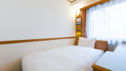 a small bedroom with a white bed and a window at Toyoko Inn Hachinohe Ekimae in Hachinohe