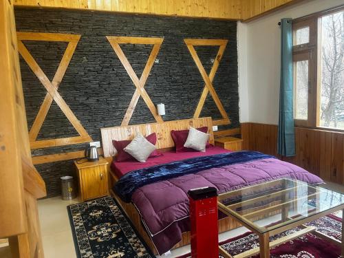 a bedroom with a purple bed with a brick wall at Cabin in the woods in Banjār
