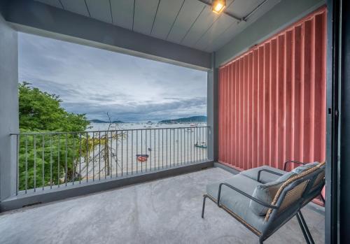 a balcony with a chair and a view of the water at SHIN Arch39 Phuket Beach Front - SHA Plus in Chalong 