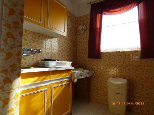 a small kitchen with yellow cabinets and a window at Fábián Apartman-ház in Szántód