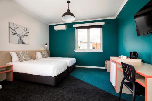 a room with two beds and a desk and a window at Greenacre Hotel in Sydney