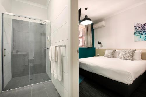 a room with a bed and a glass shower at Greenacre Hotel in Sydney