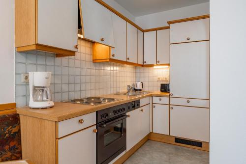 a kitchen with white cabinets and a stove top oven at Apartment Sonnberg in Mittersill