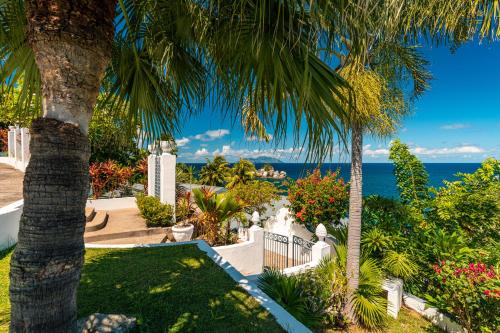 a view of a garden with palm trees and the ocean at Blue Rhapsody Villa in Glacis