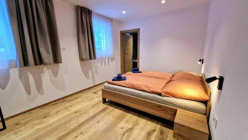 a bedroom with a bed with orange sheets and a window at Silberdistel Brand-new luxury apartment with private terrace in Saas-Fee