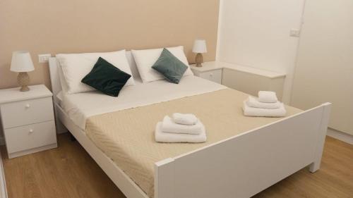 una camera da letto con un letto bianco con asciugamani sopra di Elegante matrimoniale clemente house catania centro a Catania