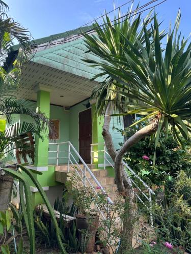 a green house with a palm tree in front of it at จันทรา รีสอร์ต เอราวัณ Jantra Resort Erawan Kanchanaburi in Tha Kradan