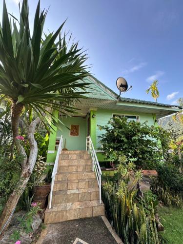 a green house with a staircase leading up to it at จันทรา รีสอร์ต เอราวัณ Jantra Resort Erawan Kanchanaburi in Tha Kradan