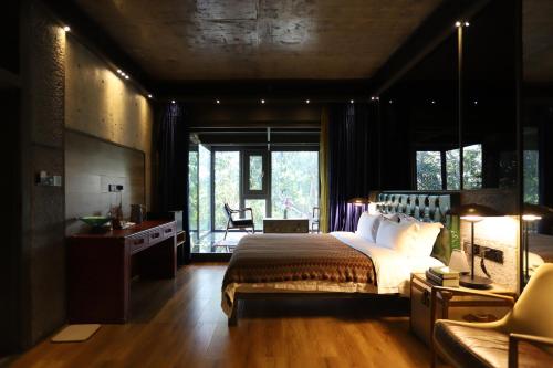 a bedroom with a large bed and a desk and a chair at Sanya Yalong Bay Danqiu Castle Manor Hotel in Sanya