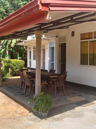 a patio with a table and chairs under a roof at Rainforest Holiday Inn in Deniyaya