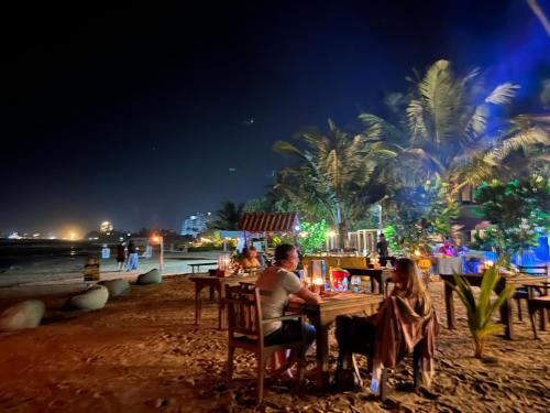a couple sitting at a table on the beach at night at Turtle Beach Club in Pelena