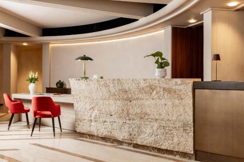 a lobby with a stone wall and red chairs at Adoro Hotel in Rome
