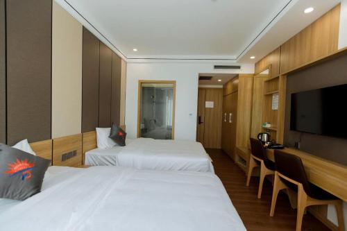 a hotel room with two beds and a flat screen tv at Phương Đông Hotel Móng Cái in Móng Cái