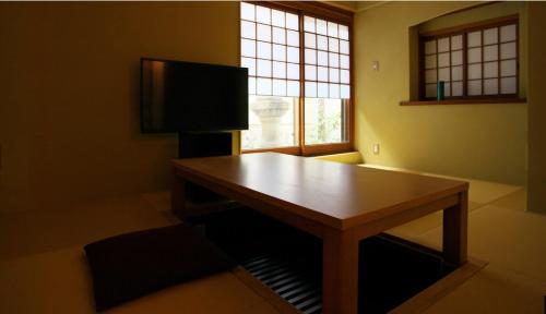 a living room with a wooden table and a television at Kyoto Kiyomizu Machiya NAGOMI in Kyoto