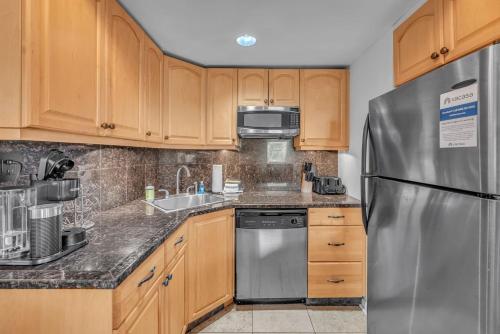 a kitchen with wooden cabinets and a stainless steel refrigerator at Honky Tonk Angels Suite in Nashville