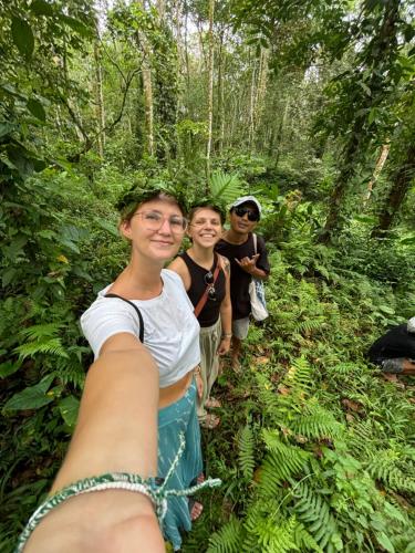 three people walking down a trail in the forest at PANORAMA BUNGALOWs in Tetebatu