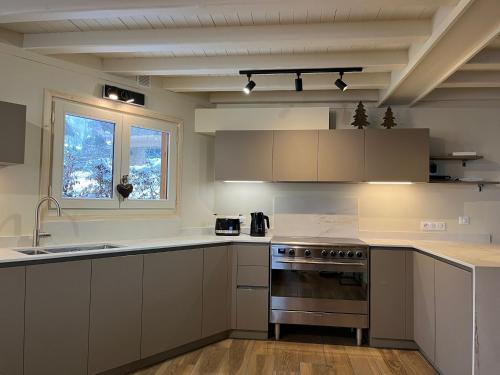 d'une cuisine avec des placards blancs, une cuisinière et une fenêtre. dans l'établissement Chalet Le Renard Du Lac, aux Gets