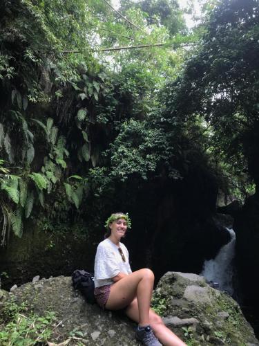 a woman sitting on a rock in front of a creek at PANORAMA BUNGALOWs in Tetebatu