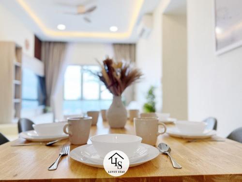 a wooden table with white dishes and a vase with flowers at Nexus Kajang MRT link - 3 BR Cozy Muji Suite # 28 in Kajang