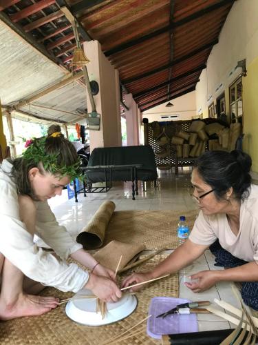 two women sitting on the floor working on a plate at PANORAMA BUNGALOWs in Tetebatu