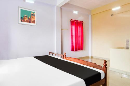 a bedroom with a bed and a red window at Hotel O Sree Badra Lodge in Trichūr