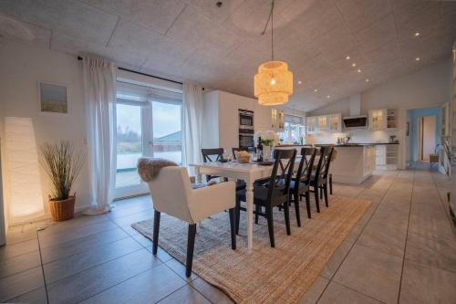 a dining room and kitchen with a table and chairs at Villa Teglgårdshaven in Sindal