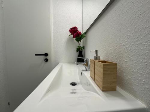 a bathroom with a sink with a flower in a vase at Attraktives City-Apartment No5 in Bremen
