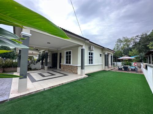 a house with a green lawn in front of it at DeCherating privatepool in Cherating
