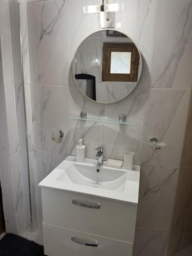 a white bathroom with a sink and a mirror at Cases conviviales et chaleureuses in Sali Tapé