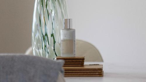 a bottle on a wooden stand next to a vase at Modern And Cozy Apex Apartment in Helensburgh