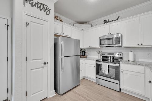 Una cocina con gabinetes blancos y un refrigerador de acero inoxidable. en Modern 3BR in Gated Community Near JBSA & SeaWorld Duplex, en San Antonio