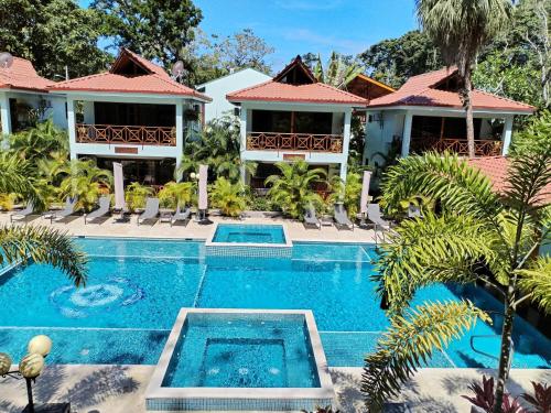 a villa with a swimming pool in front of a house at Bungalows Beachfront Hotel in Punta Uva