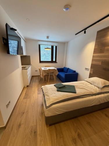ein Schlafzimmer mit einem Bett, einem Tisch und einem blauen Sofa in der Unterkunft Juli Kop in Kopaonik