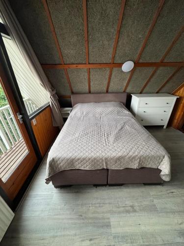 a bedroom with a bed and a dresser and windows at Lovely house till 9 pers near Amsterdam and the sea in Opmeer