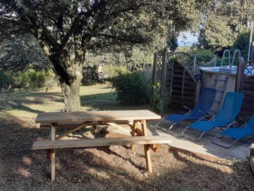 une table de pique-nique en bois et un banc à côté d'un arbre dans l'établissement Chambres d'hôtes Des couleurs et des Mots, à Villeuneuve-de-Berg