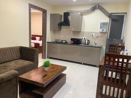 古尔冈MY STAY Service Appartment的客厅配有沙发和餐桌,厨房配有桌子