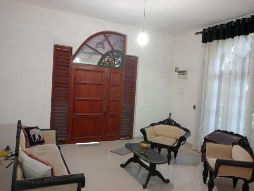 a living room with a wooden door and chairs at Rock View Bungalow - Home Stay - Kandy in Kandy