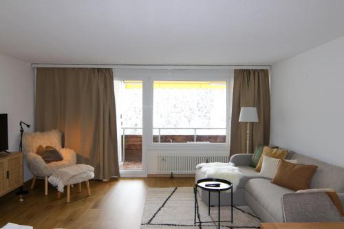 Una sala de estar con un sofá y una ventana. en Rothornblick 50 by Arosa Holiday, en Arosa