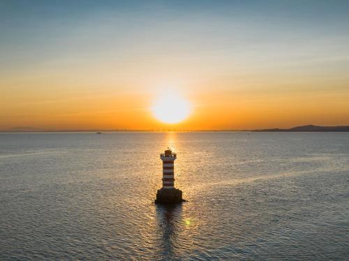 a lighthouse in the water with the sunset in the background at Shangri-La Xiamen in Xiamen