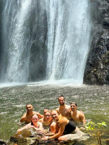 a group of people in the water in front of a waterfall at Lazy Cat Homestay - Motorbikes Rental & Tours in Ha Giang