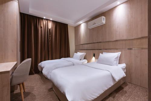 a hotel room with two beds and a desk at Second Home Hospitality, Rehab City, New Cairo, Cairo Egypt in New cairo