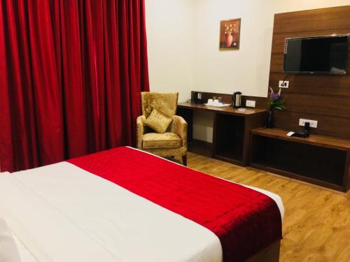 a hotel room with a bed and a chair and a desk at Hotel Bahl Regency in Zirakpur