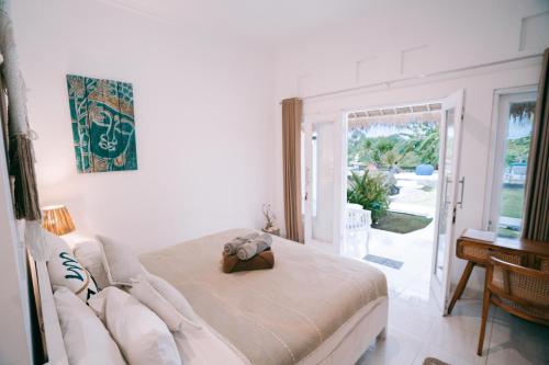a bedroom with a bed and a table and a window at Sukacita Hill in Uluwatu