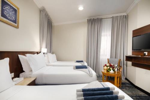 a hotel room with two beds and a flat screen tv at Emaar Al Khalil in Makkah