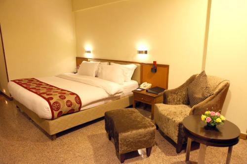 a hotel room with a bed and a chair at Lords Plaza Surat in Surat