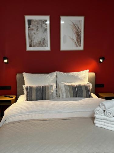 a bedroom with a white bed with a red wall at Salt Garden Apartments in Druskininkai