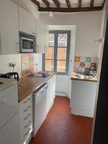 une petite cuisine avec des armoires blanches et un évier dans l'établissement BIOT-Charmant et coquet F2, à Biot