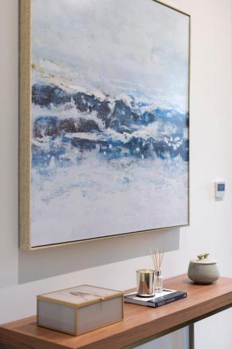 a painting hangs on a wall above a table with a book at City Escape - Stylish Studio in Central Reading - CHRL F16 in Reading