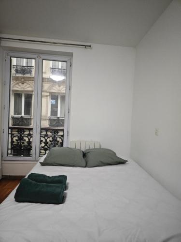 un lit blanc dans une chambre blanche avec une fenêtre dans l'établissement Séjour à Gare de l'Est, à Paris