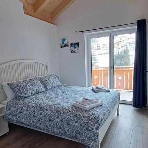 a bedroom with a bed and a large window at Dream Apartments Moena in Moena